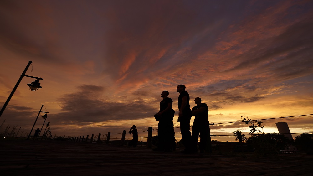 Firefighters stare at a sea wall at sunset as they wait for Hurricane Laura to make landfall on Wednesday [Eric Gay/AP]